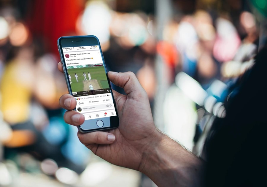 A person holding a phone displaying NV Play's cricket analysis app.