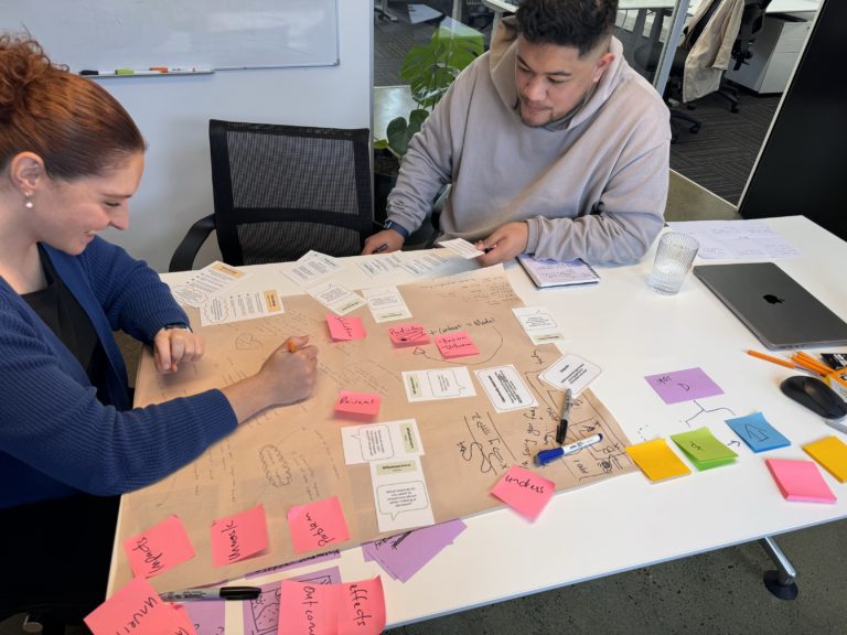 Workshop participant explaining an idea with a facilitator at a table